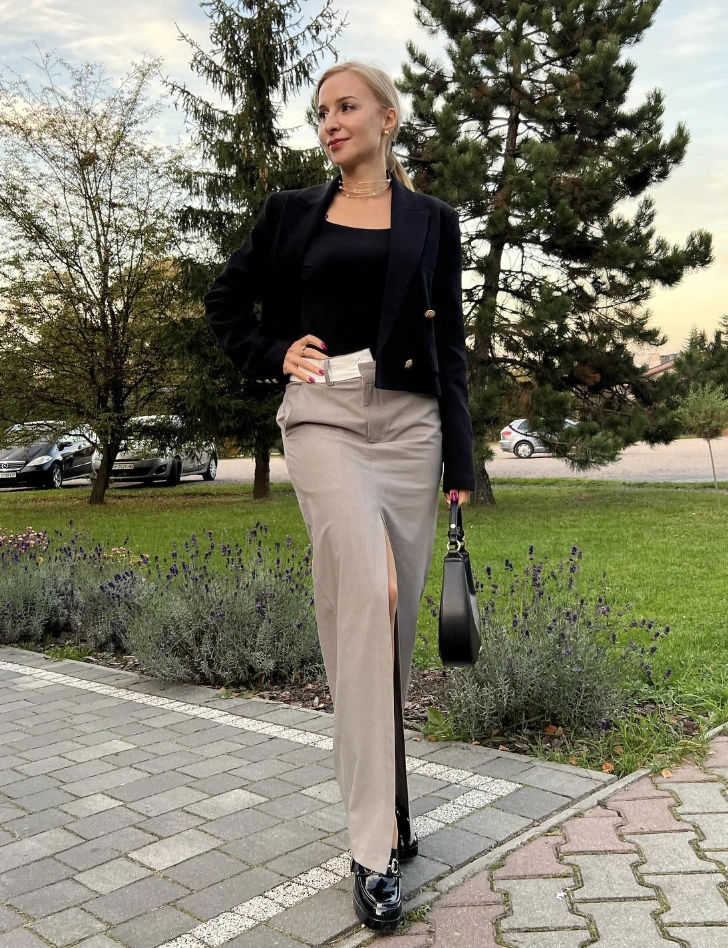 A formal grey skirt with a high slit, paired with a fitted black blazer and a stylish handbag, perfect for business meetings.